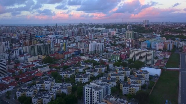 Urban high-rises in Macei&oacute; under scattered clouds catching bright pink sunset light. Aerial ascent over buildings. Recorded in 4K at 25 fps.