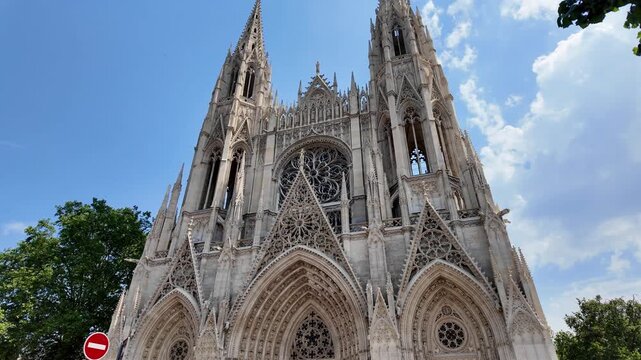 Sunny view of the Abbatiale Saint-Ouen in the historic center of Rouen, featuring soaring Gothic towers and intricate stonework.