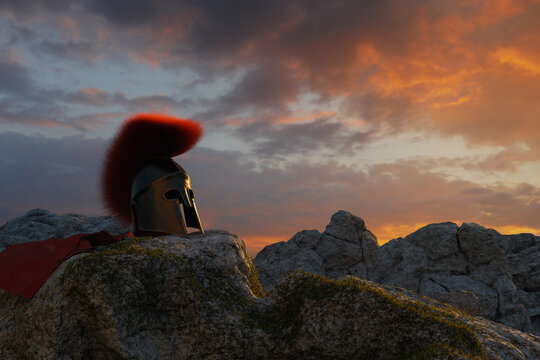 3D Rendering of an anncient greek Sparta helmet with red cape laying on rocks in the evening sunset