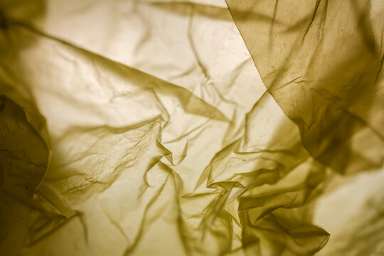 Extreme close up of yellow plastic texture background. The plastic surface is wrinkly and tattered making abstract pattern. Selective focus, shallow depth of field.