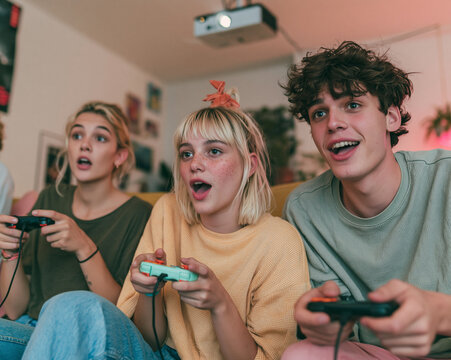 Group of excited young friends playing video games with joysticks at home