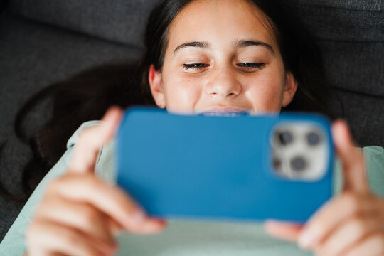 Female teen using smartphone while watching a reel video on social media - Technology addiction and teenager lifestyle concept - Main focus on face