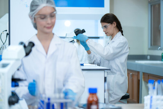 Female scientist using a microscope while conducting scientific research and analyzing samples