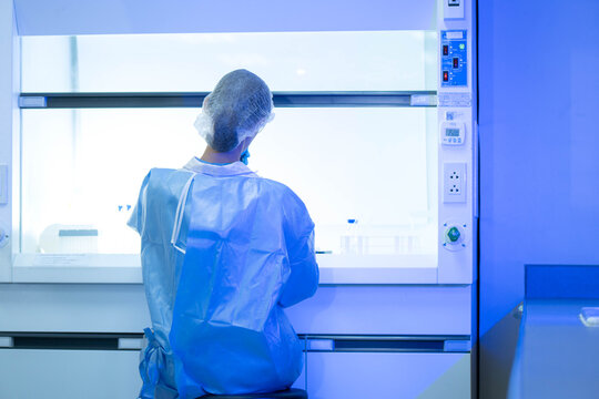 Scientist working inside a laboratory safety cabinet while conducting controlled scientific research and sample preparation