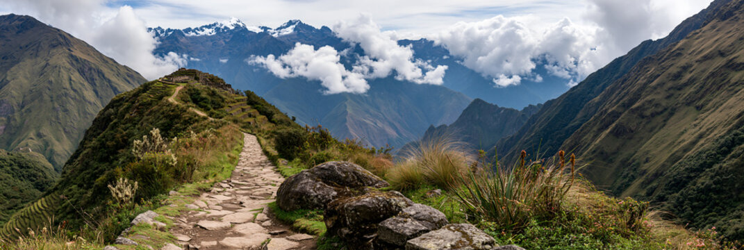 impressive historic inca road winding through the andes, ancient stone path across dramatic mountain terrain, remote inca trail surrounded by terraces and snowcapped peaks