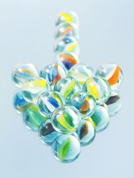 Colorful glass marbles arranged in arrow shape with reflection on light blue surface
