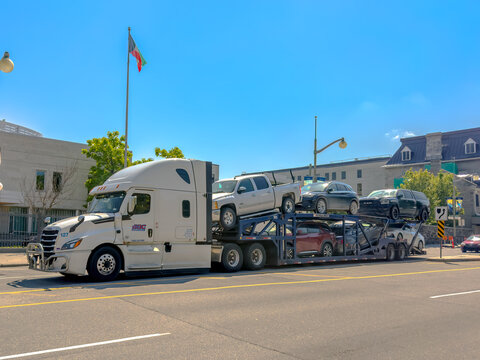 Ottawa, ON, Canada. Aug 20, 2026. Side view of a white Freightliner car hauler semi-trailer truck carrying automobiles on an urban street.
