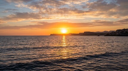 Fototapeta premium Golden sunset reflecting on the ocean waves and distant cliffs