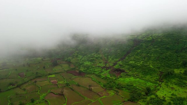 Scenic Aerial View of the Sahyadri Mountains Covered in Floating Clouds with Small Waterfalls Cascading Down Lush Green Slopes, Monsoon Landscape, Misty Hills, Dense Forest and Breathtaking Western Gh