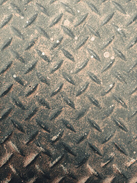 Perspective close-up view of a dusty diamond plate metal floor texture