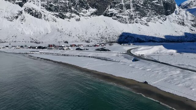 Aerial View of Snow-Covered Coastal Road and Fishing Village by Fjord in Senja Island Norway