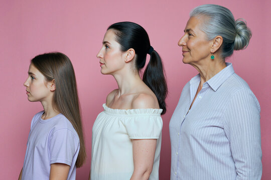 Caucasian girl, young adult woman, senior woman standing in side profile against pink background, showing female generations and aging. Ideal for family marketing, skincare, wellness campaigns