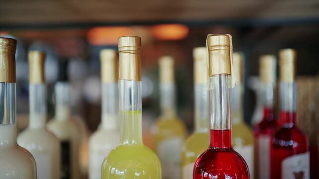 Selection of colorful liqueur bottles displayed on wooden shelves inside specialty shop.