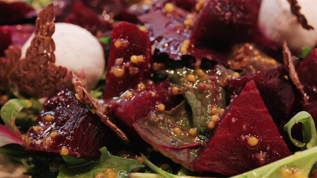 Fresh beetroot salad with goat cheese and flaxseed crackers presented on white plate.