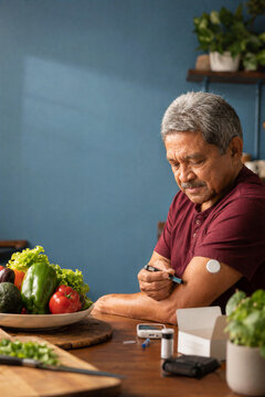Senior man using an insulin pen with glucose monitor during diabetes self-care