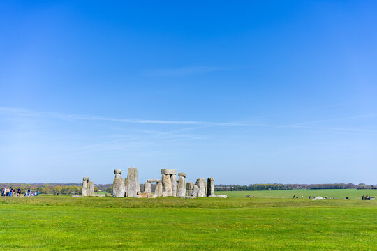 Stonehenge, prehistoric stone circle on Salisbury Plain in Wiltshire, England seen from the distance with a group of people on the left