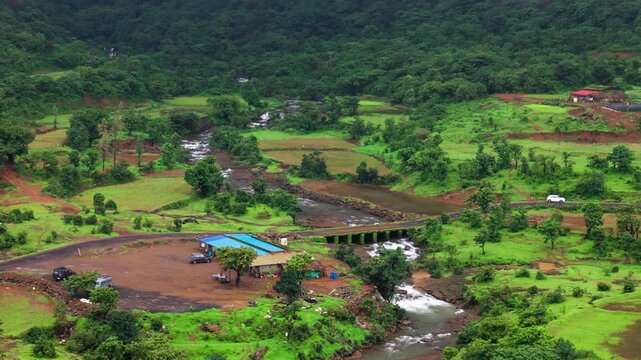 Scenic Aerial View of a Small Open Bridge Crossing a Flowing River in Maharashtra During Monsoon, Lush Green Mountains, Rainy Landscape, Strong Water Current, Misty Hills and Breathtaking Sahyadri Sce