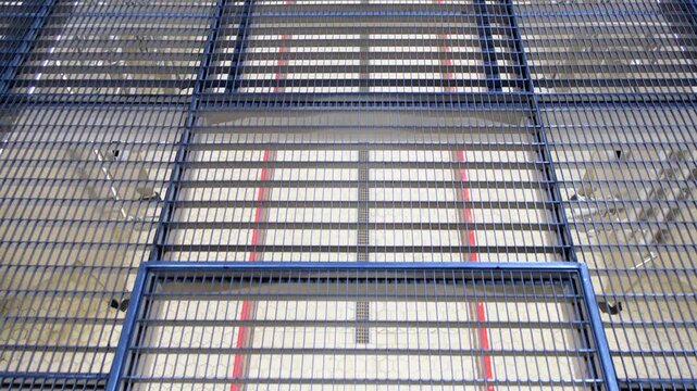 Slow camera movement over industrial metal mesh grating walkway on elevated mezzanine level in modern factory or high-tech facility. Steel grid flooring close-up view