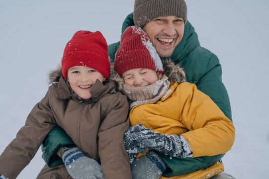 Father and sons smiling outdoors in winter snow wearing warm clothing