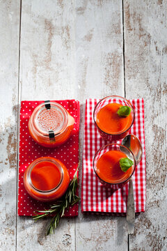 Glasses and preserving jars of tomato soup garnished with basil leaves