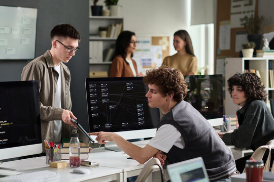Students discuss programming on a tablet in the university classroom