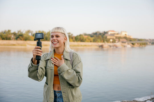 Travel vlogger making video and talking by the riverside outdoors