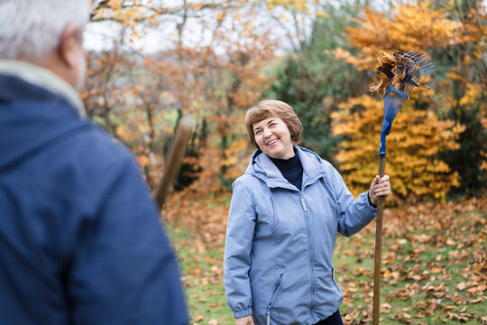 A man and woman rake autumn leaves in the garden