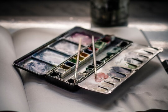 Used water colour paint box and two brushes on sketchbook