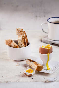 Egg in egg cup with toasted white bread and coffee mug, close up