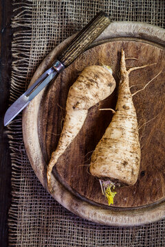 Parsley roots and peeler on wooden board and jute