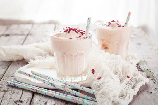 Two glasses of vanilla milkshake with dried raspberries