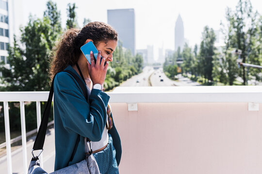 Young woman on bridge talking on cell phone