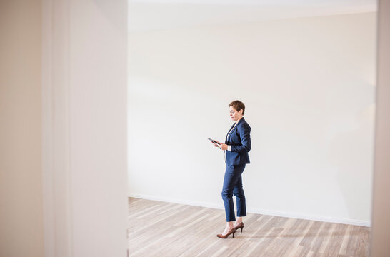 Woman in empty apartment with tablet
