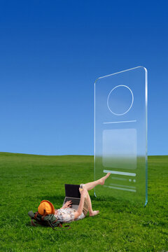 Remote worker reclining on grass with laptop beside transparent profile interface and copyspace. Concept of mobile office, travel apps and independent business.