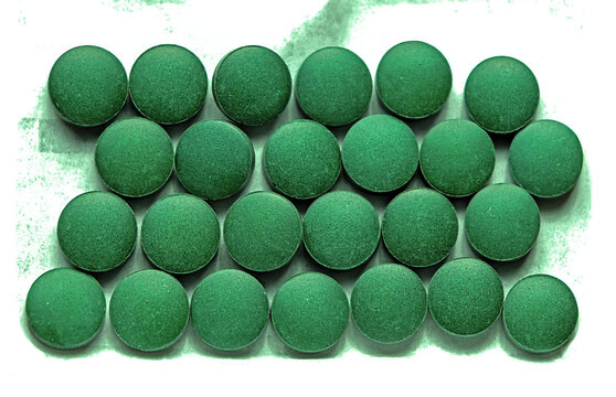 Healthy green spirulina food supplement tablets on white