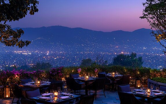 Restaurante rom&acirc;ntico ao ar livre com vista para a cidade ao anoitecer.