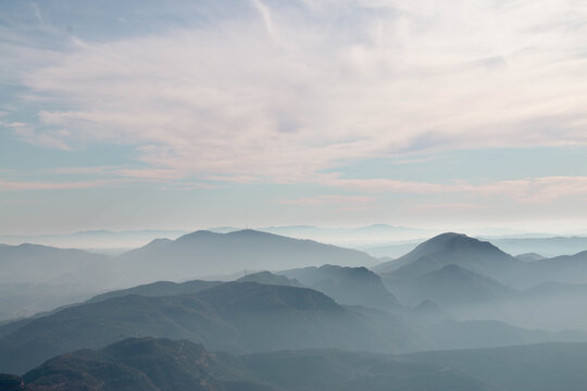 Layered mountain ranges fading into the mist under the soft clouds