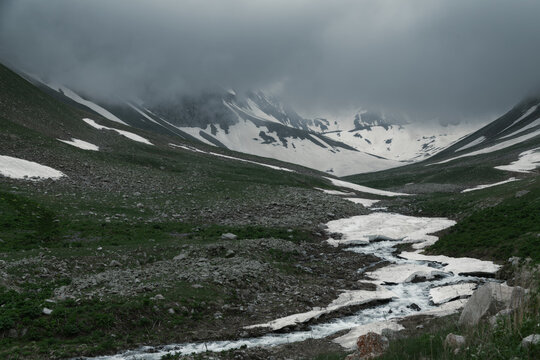 Moody Mountain Valley With a Winding Meltwater Stream Under a Dark Sky