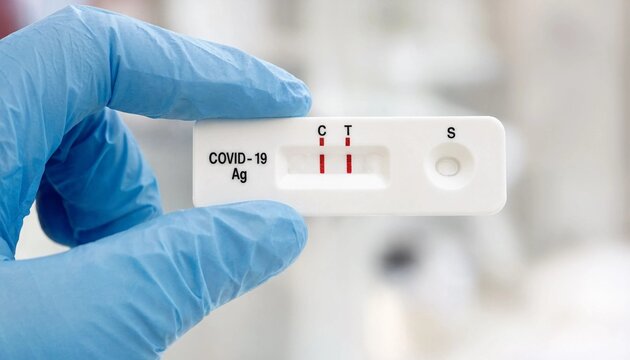 A hand wearing a blue medical glove holding a positive rapid antigen test for covid19 detection
