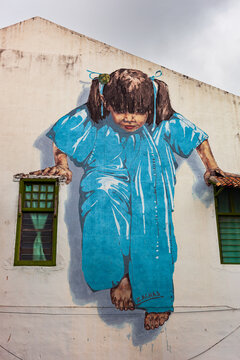 Street art mural depicting a young girl on the wall of a historic building in George Town, Penang, Malaysia.