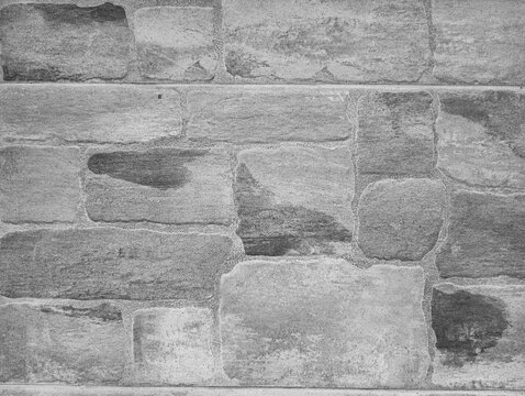 Black and white texture of a modern tile wall mimicking old rustic stone masonry with textured concrete mortar joints.