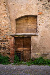 Fototapeta premium Ancient barred wooden door and stone architecture in Garessio, Piedmont, Italy.