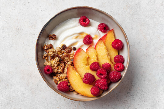 Granola bowl with yogurt, peach, raspberry and honey