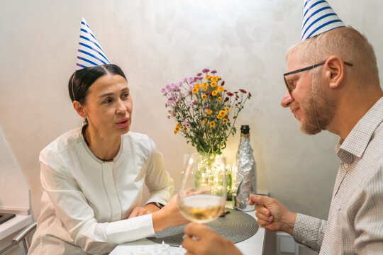 Couple Birthday Party Celebration: Indoor intimate birthday celebration featuring a couple wearing party hats, toasting with wine.