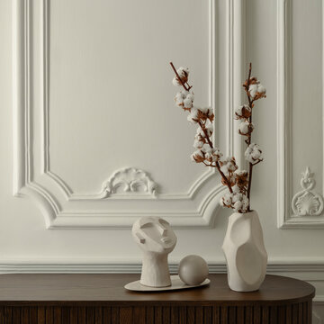 Minimalist interior decor with abstract white ceramic sculpture and cotton branch in vase against classic wall molding background for home design