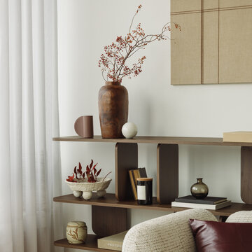 Minimalist modern wooden shelf decorated with vases, plants, books, and art in a bright living room interior with cozy home decor atmosphere