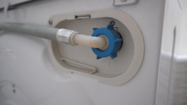 The water supply pipe to the washing machine. The back of the washing machine. Washing machine pipes.