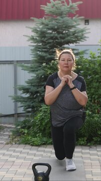Senior overweight woman exercises outside. Woman lunges