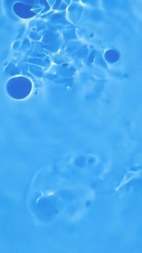 Abstract blue water surface with gentle ripples, bubbles, and shimmering sunlight reflections creating fluid patterns, refreshing aquatic texture, and a relaxing summer background.