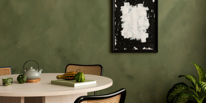 Modern dining room interior with a round wooden table, green textured wall, black framed abstract wall art, teapot, and decor elements